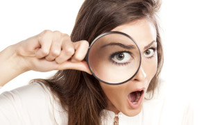 shocked young woman looking through a magnifying glass